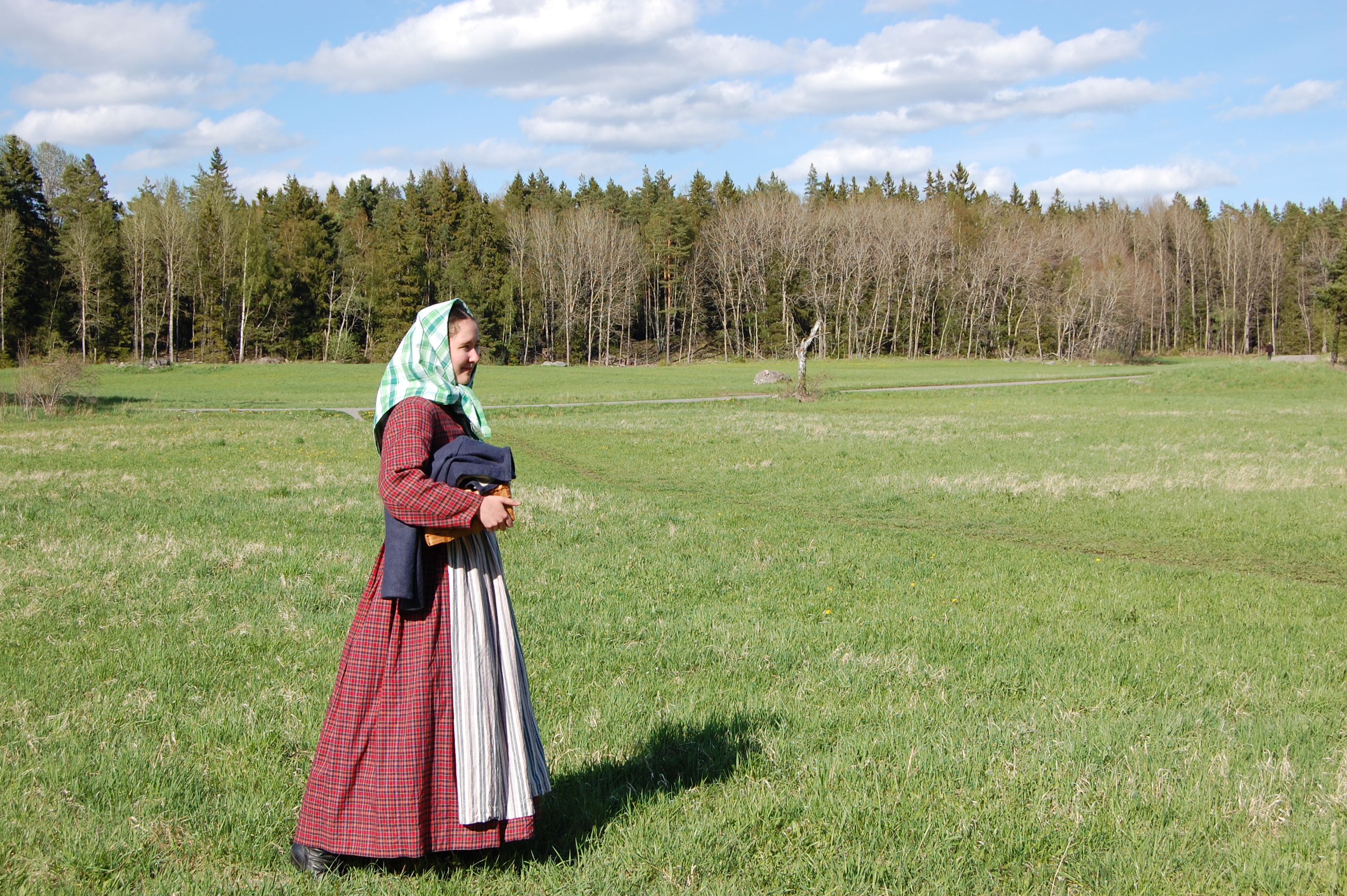 I rutig 1850-talsklänning och sjalett på stor äng