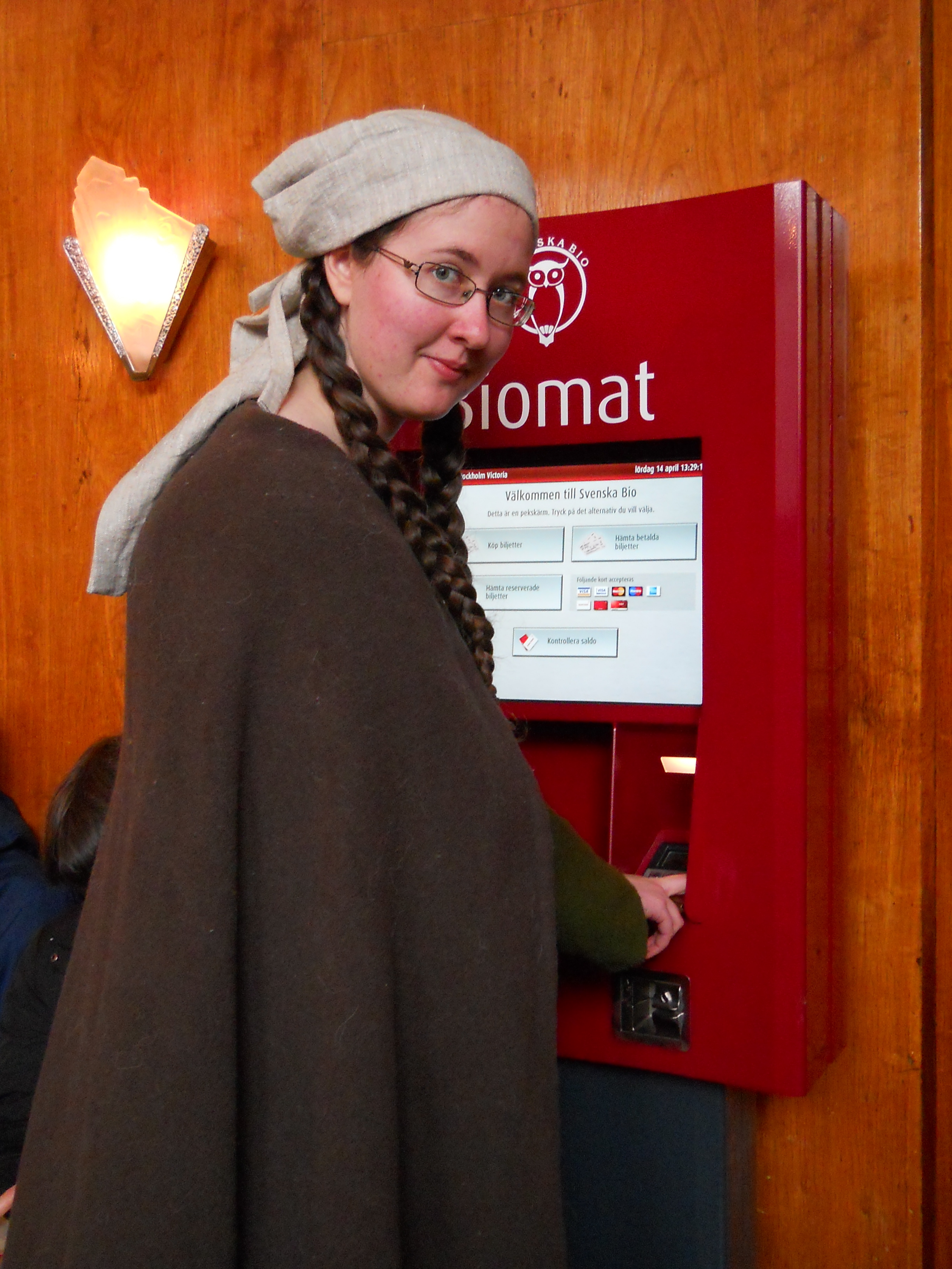 Står vid bioautomat i medeltidskläder