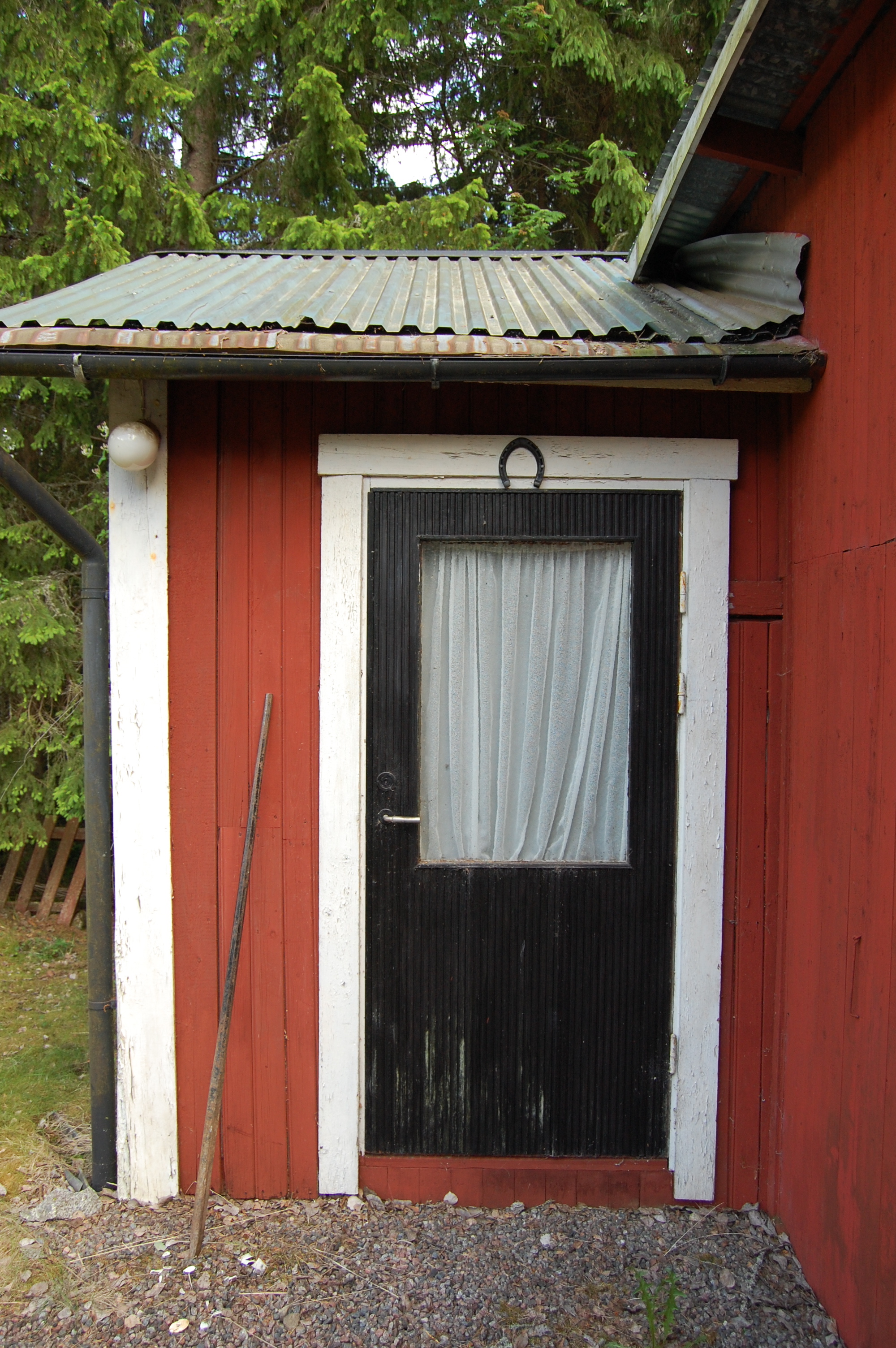 Svart dörr med stort fönster och hästsko över.